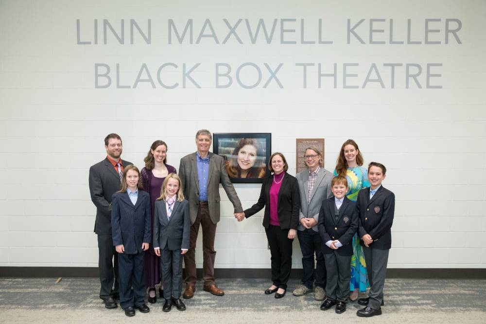 Another photo of the family posing in front of the photo of Linn Maxwell Keller.